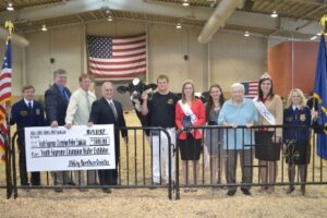 Sam Yoder (blue shirt) stands with the 2012 Premier National Junior Events Supreme Champion Heifer Peace & Plenty Ast Fishy exhibited by Austin Schwartzbeck of Union Bridge, Md. Schwartzbeck received the Samuel Yoder Crystal Star Award.